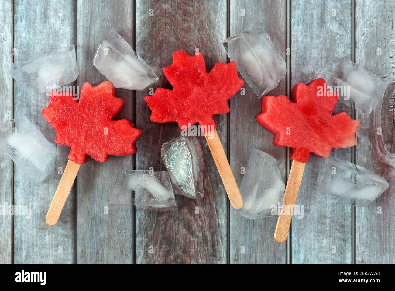 L'anguria canadese in foglia di acero si popola con cubetti di ghiaccio su uno sfondo rustico di legno invecchiato Foto Stock
