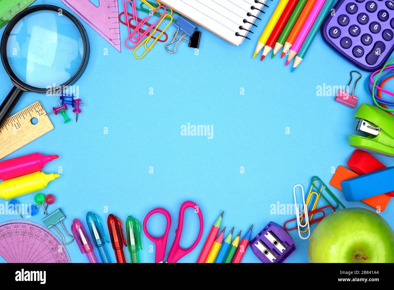 Le forniture scolastiche si inquadrano su uno sfondo di carta blu Foto Stock