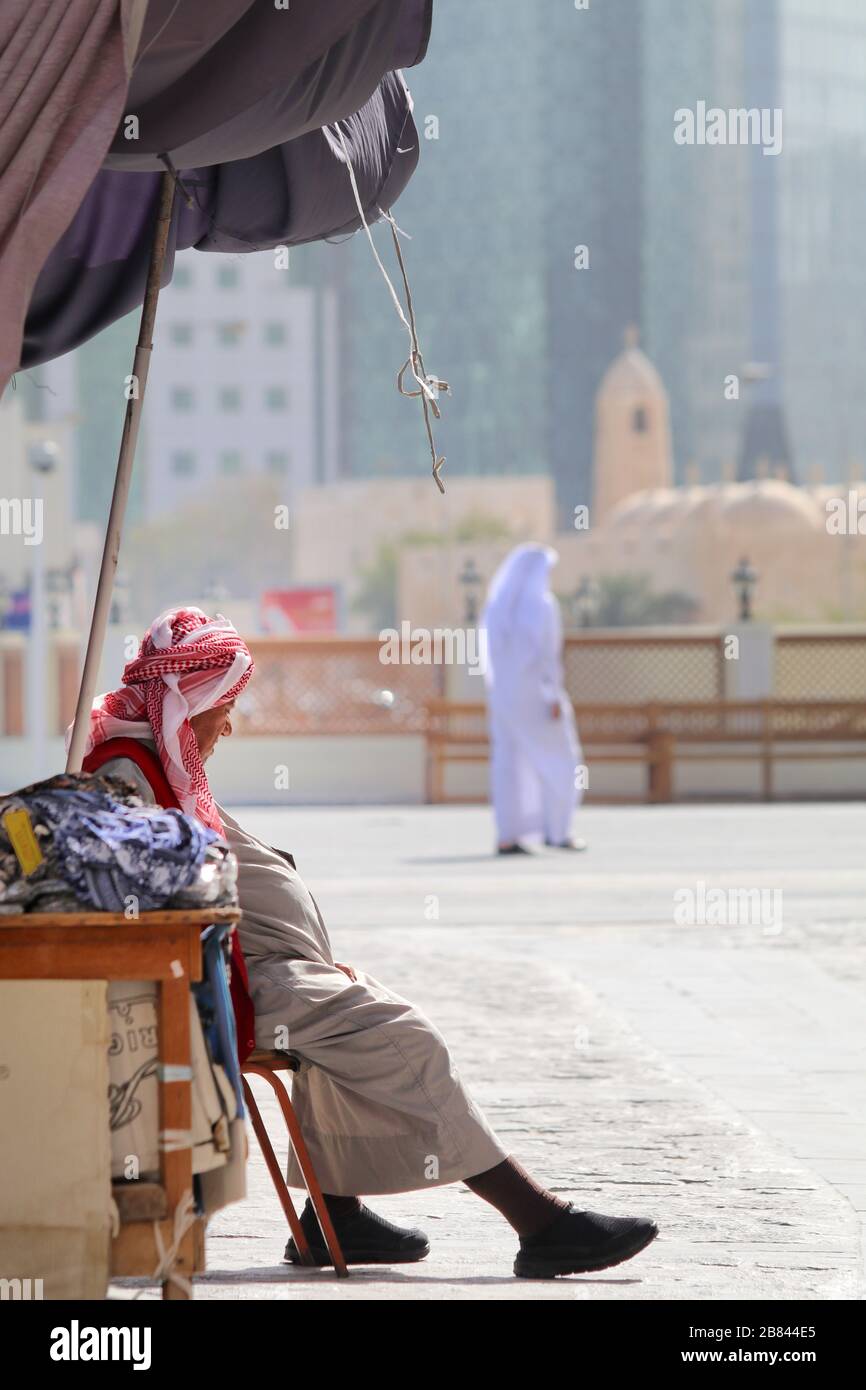 Un vecchio uomo seduto fuori dal suo negozio in attesa di un cliente a Doha, Qatar Foto Stock