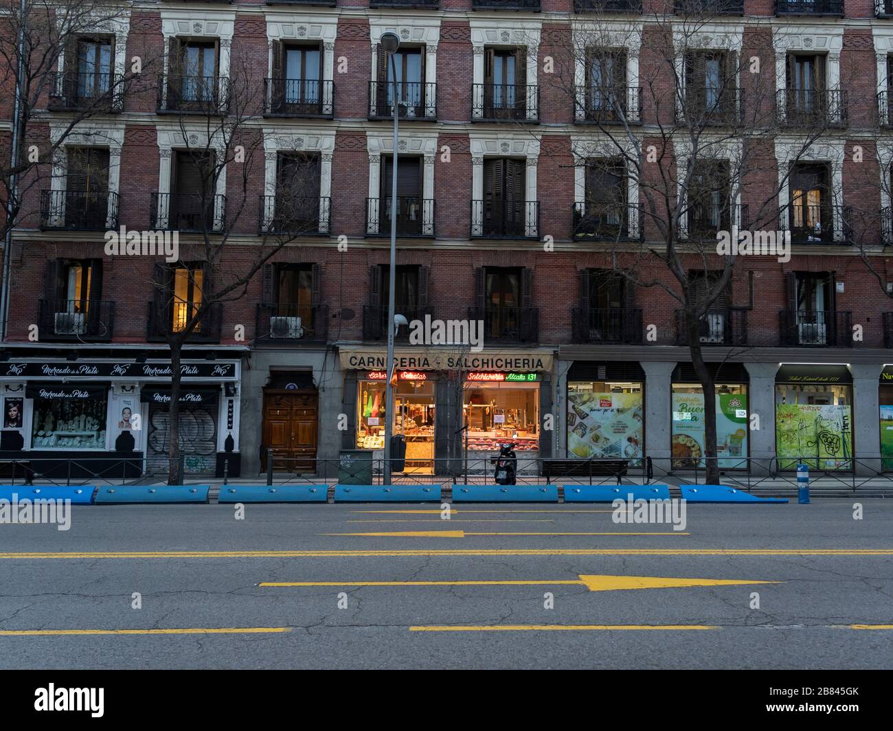 Un macellaio rimane aperto nel mezzo di una strada vuota Alcalá, nel centro di Madrid, seguendo il blocco dei coronavirus. A partire dal 15 marzo, ogni negozio che non ha bisogno di prima deve rimanere chiuso fino a quando lo stato di allarme dura. Foto Stock