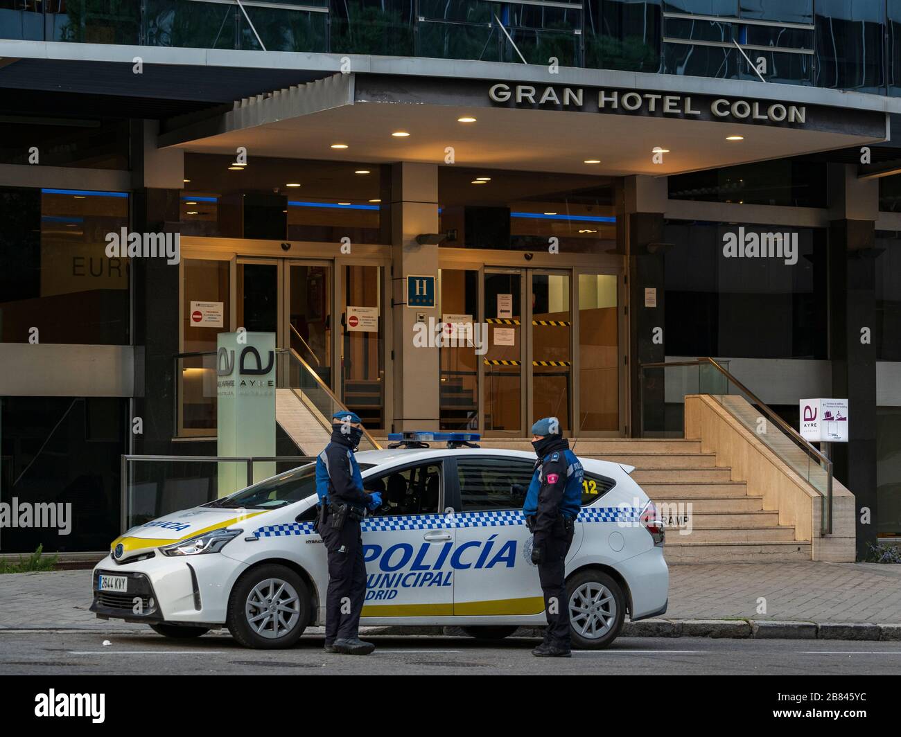 Due poliziotti comunali di Madrid hanno una chiacchierata mentre sorvegliano l'ingresso principale dell'hotel Gran Hotel Colon, nel centro di Madrid. Il 19 marzo, il Gran Hotel Colon è diventato il primo hotel medicalizzato in Spagna che ospita pazienti con sintomi blandi del coronavirus. È vietato l'accesso a persone non autorizzate. L'hotel dispone di 365 camere da letto per ospitare pazienti affetti da coronavirus nel tentativo di alleviare la pressione degli ospedali affollati. Foto Stock