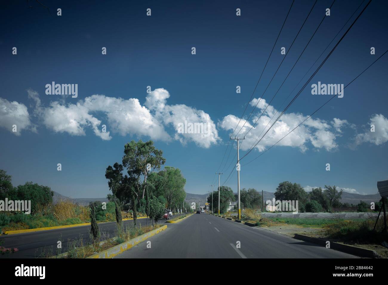 Autostrada in Messico rurale con nuvole di cumuli e cielo blu sullo sfondo Foto Stock