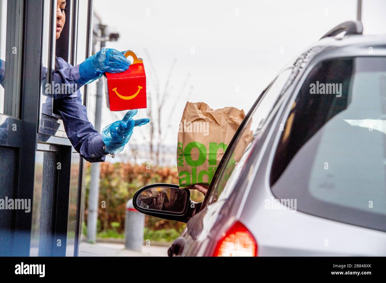 Schiphol, Paesi Bassi. 18 Marzo 2020. Un dipendente che indossa i guanti come protezione visto dare cibo a un cliente a un McDonald's Mac Drive in Coronavirus (Covid-19) fear.Netherlands's Ministero della Salute ha registrato un totale di 2,460 infezioni, 76 morti e 2 recuperati dall'inizio del focolaio. Credit: SOPA Images Limited/Alamy Live News Foto Stock