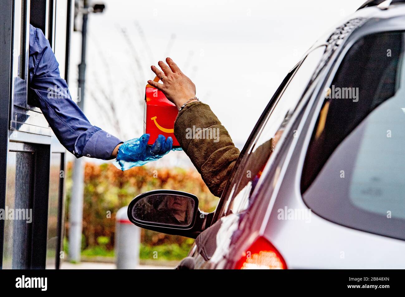 Schiphol, Paesi Bassi. 18 Marzo 2020. Un dipendente che indossa i guanti come protezione visto dare cibo a un cliente a un McDonald's Mac Drive in Coronavirus (Covid-19) fear.Netherlands's Ministero della Salute ha registrato un totale di 2,460 infezioni, 76 morti e 2 recuperati dall'inizio del focolaio. Credit: SOPA Images Limited/Alamy Live News Foto Stock