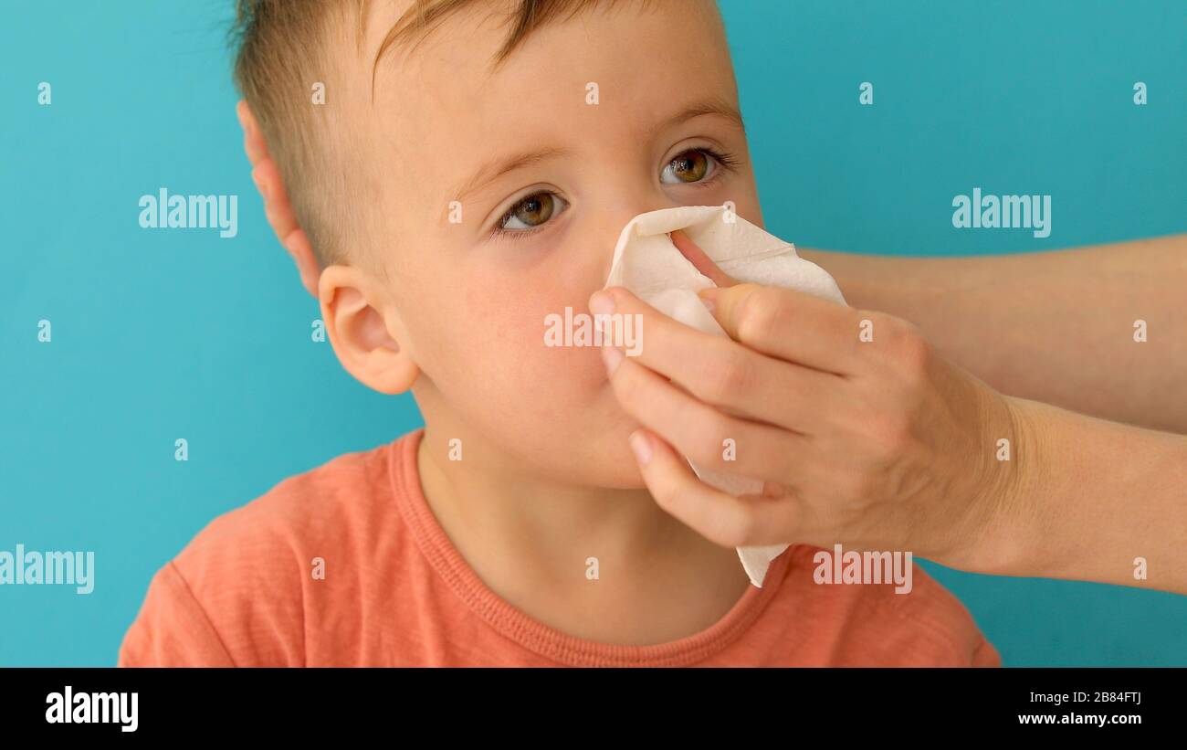 L'adulto aiuta il bambino a soffiare e pulire il naso che corre Foto Stock