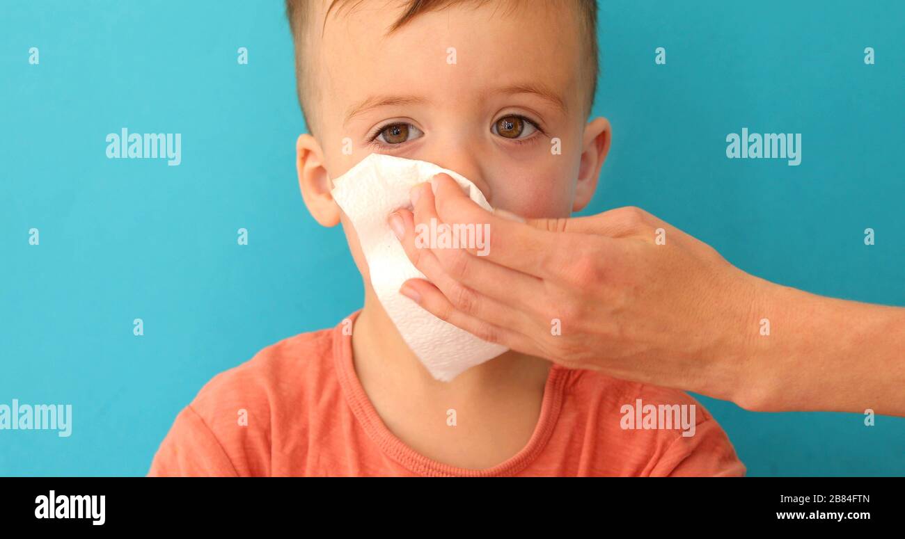 L'adulto aiuta il bambino a soffiare e pulire il naso che corre Foto Stock
