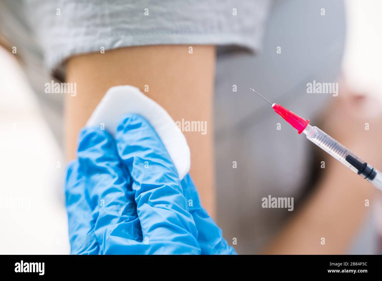 Primo piano di UN medico che inietta la siringa al braccio della paziente femminile in clinica Foto Stock