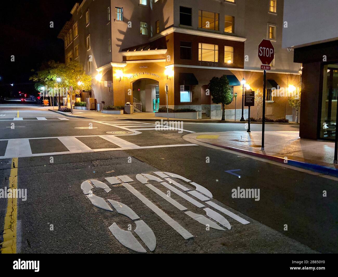 San Luis Obispo, California, Stati Uniti. 19 Mar 2020. Una strada vuota con un fatale segnale di stop di fronte all'edificio del Municipio, ora coperto, come tutto viene a una fermata improvvisa nella zona di solito vivace centro della costa centrale città universitaria di San Luis Obispo (SLO). A partire dalle 10:00 pm Giovedi, tutti i residenti della contea di San Luis Obispo sono tenuti a prendere rifugio nelle loro case, per impedire la diffusione di coronavirus, e sono invitati a non andare fuori tranne che per scopi essenziali.questo include gli studenti Cal Poly che vivono in dormitori, che sono stati chiesti di andare a casa. La Contea di San Luis Obispo Foto Stock