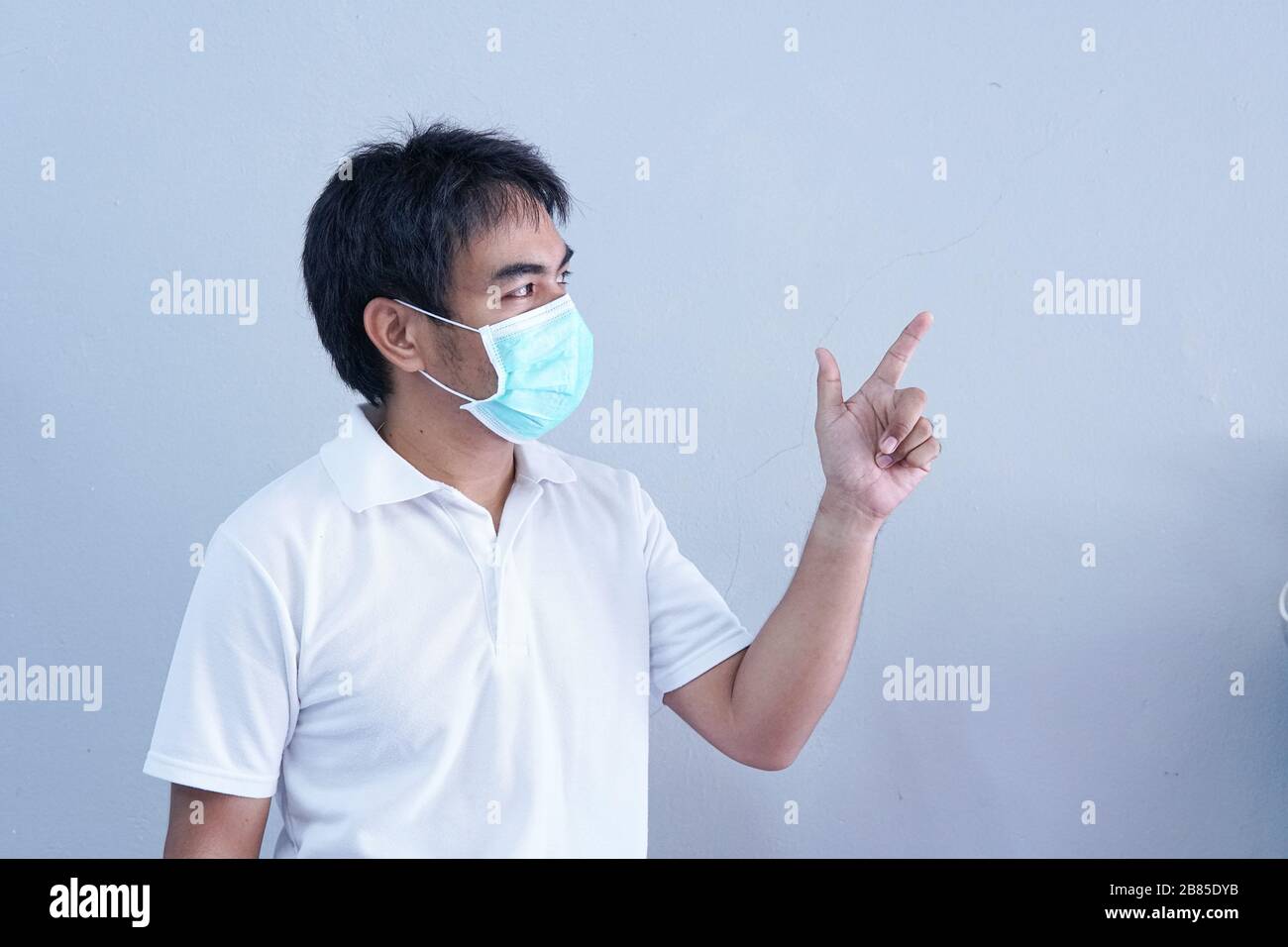 Uomo asiatico in maschera medica malattia pandemica di Coronavirus su sfondo grigio. COVID-19 virus da epidemia di Cina a globale recessione concetto per Foto Stock