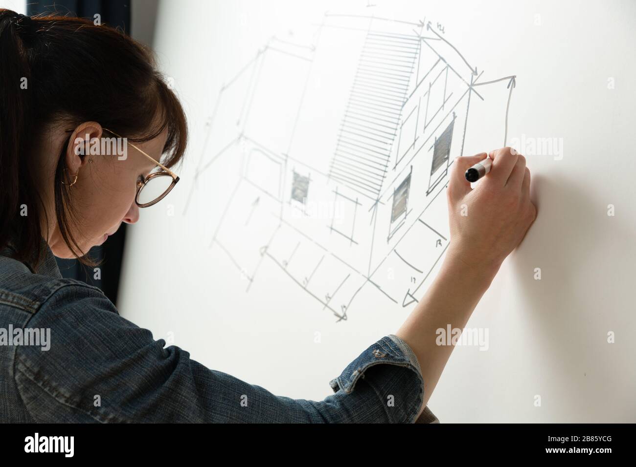 Primo piano di una giovane architetto femminile disegnando un disegno per un nuovo progetto famaly home. Concetto di lavoro su disegni tecnici Foto Stock