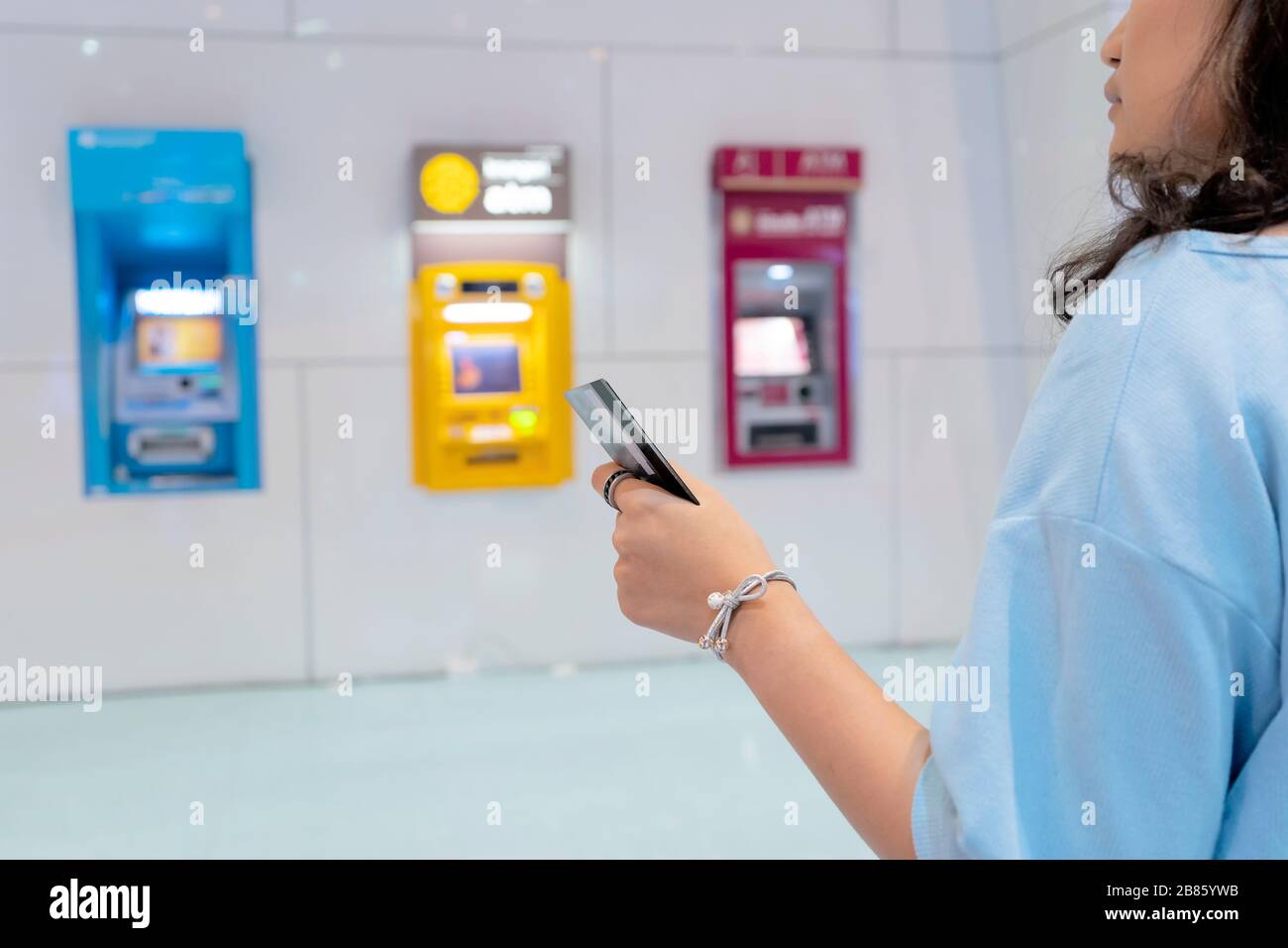 Donne che sono in possesso di carte bancomat, e lei sta scegliendo di utilizzare un gabinetto di servizio bancario. Foto Stock