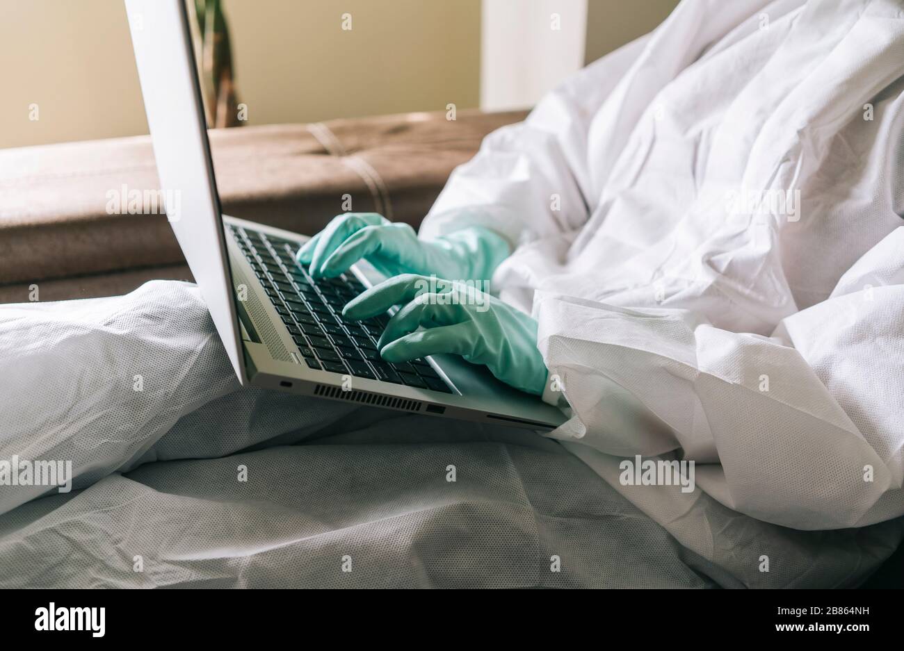 Una donna lavora da casa con il laptop, il tablet digitale e il telefono cellulare nel soggiorno, dotato di misure di sicurezza contro un virus preventio Foto Stock