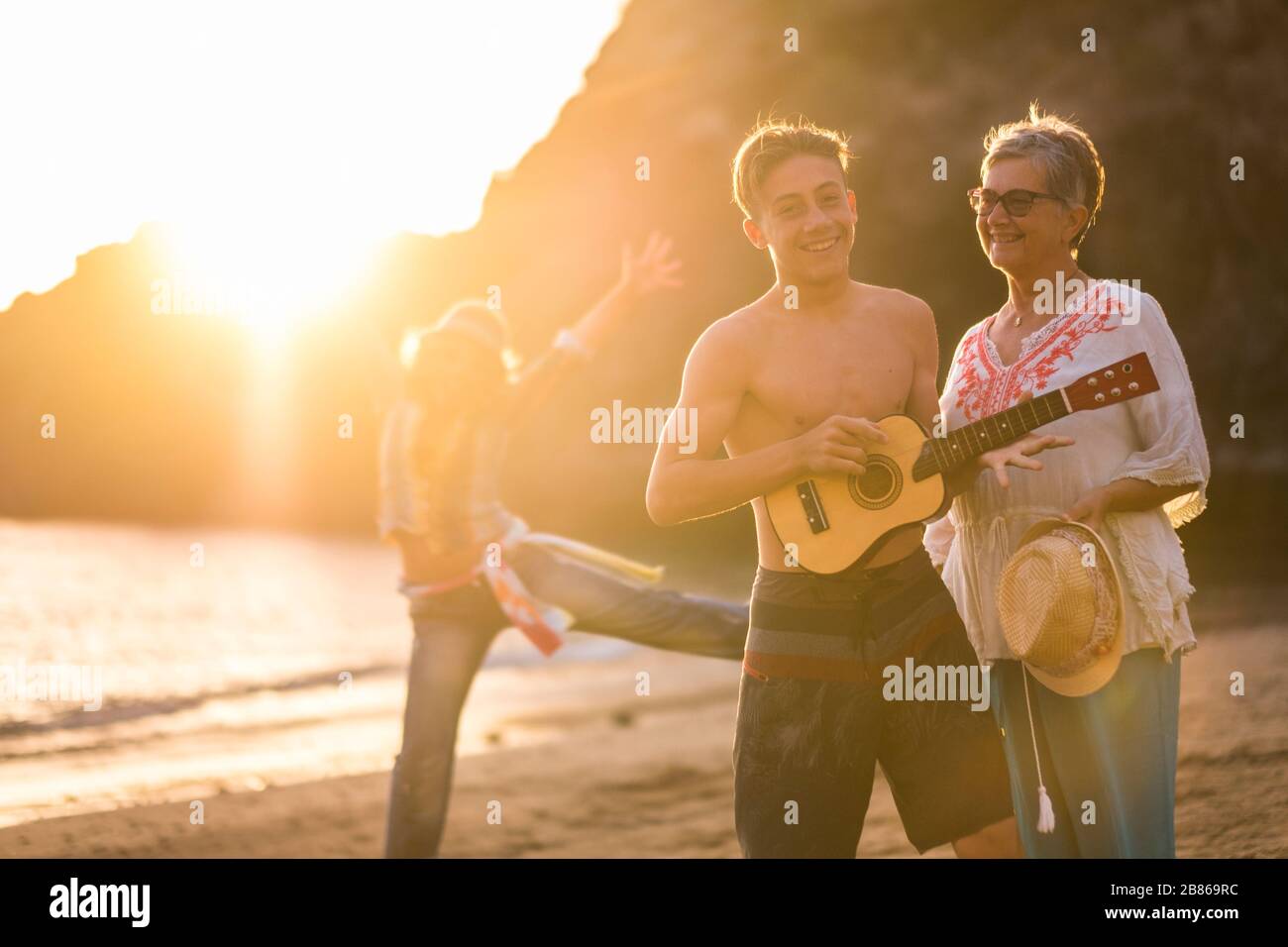 Buona famiglia divertirsi in spiaggia con una chitarra - generazioni miste da nipote a nonna e madre insieme avere felicità - gioiosa peopl Foto Stock
