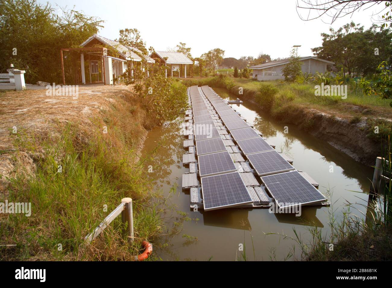 Pannello di generazione di energia solare installato sull'acqua nello stagno, che riflette il sole e cielo blu che è l'uso più produttivo in una zona limitata. Foto Stock