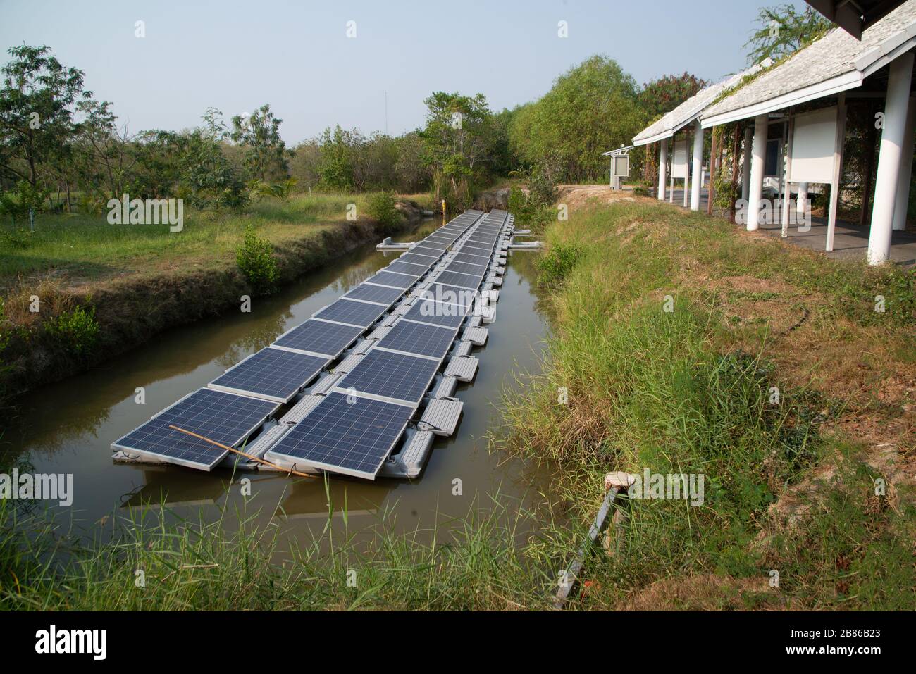 Pannello di generazione di energia solare installato sull'acqua nello stagno, che riflette il sole e cielo blu che è l'uso più produttivo in una zona limitata. Foto Stock