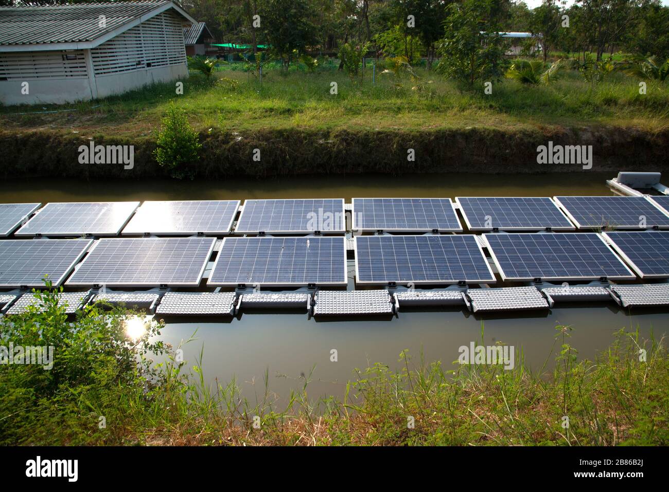 Pannello di generazione di energia solare installato sull'acqua nello stagno, che riflette il sole e cielo blu che è l'uso più produttivo in una zona limitata. Foto Stock