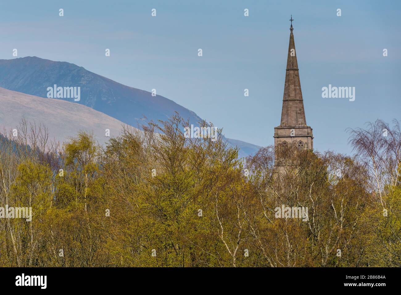 La guglia di Keswick St John con Blease cadde e Blencathra dietro visto dal Crow Park sulla riva settentrionale di Derwentwater a Keswick, in aprile Foto Stock