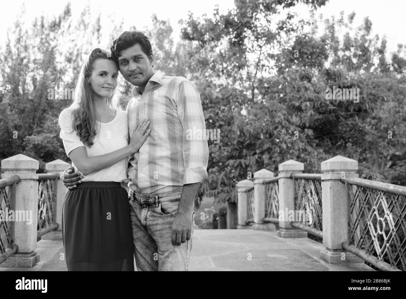Coppia multietnica innamorata sul ponte del parco Foto Stock