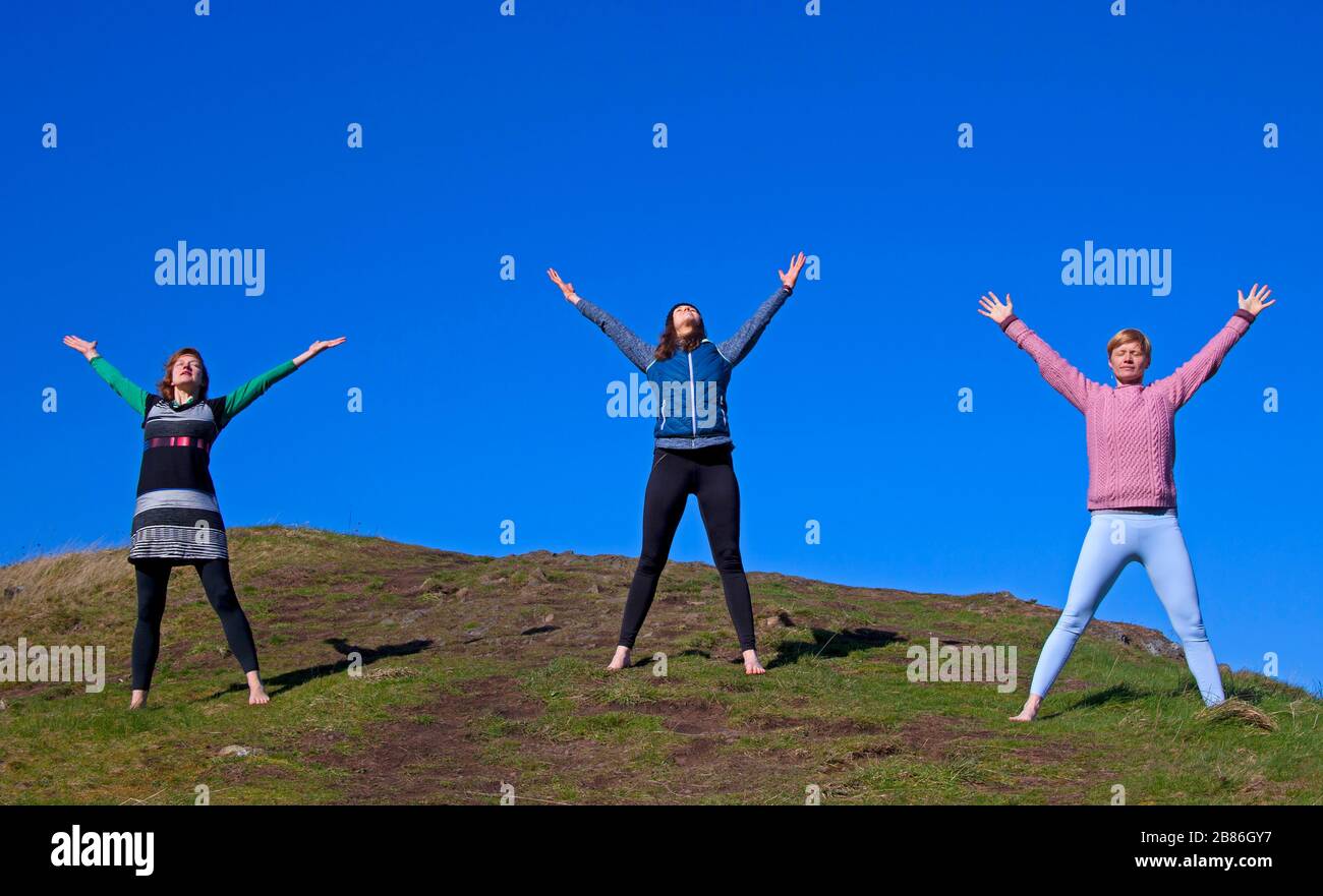 Holyrood Park, Edimburgo, Scozia, Regno Unito. 20th Mar 2020. Soleggiato, e la temperatura di 6 gradi centigradi, incoraggia queste giovani Signore a (con spazio adeguato) prendere un po 'di tempo per respirare e meditare mentre praticare yoga esercizi nella fresca ma fresca aria, garantendo di mantenere la loro distanza sociale l'uno dall'altro. Nella foto: Da sinistra a destra, Jennifer, Belinda e tutor Anna di WanderWomen Scotand. Foto Stock