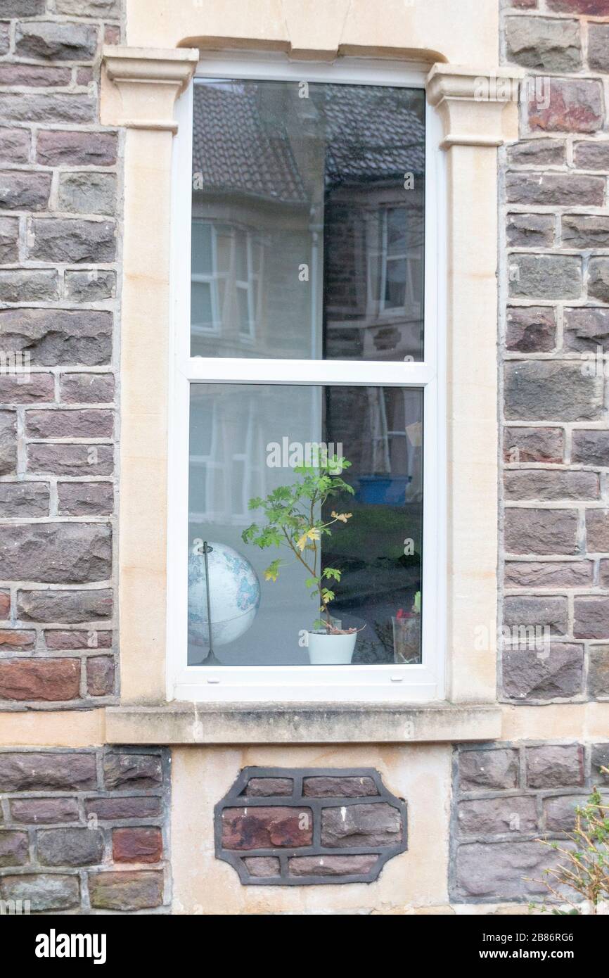 una vista ravvicinata dell'interno di una finestra di casa con un mondo globo e pianta nella finestra Foto Stock