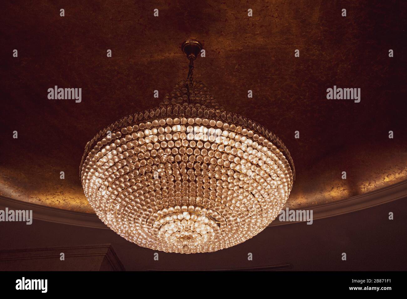 Lampadario elegante dorato lucido decorato con scintillanti pendenti a forma di diamante assomiglia a gioielli. Splendida lampada a sospensione appesa al soffitto. Foto Stock