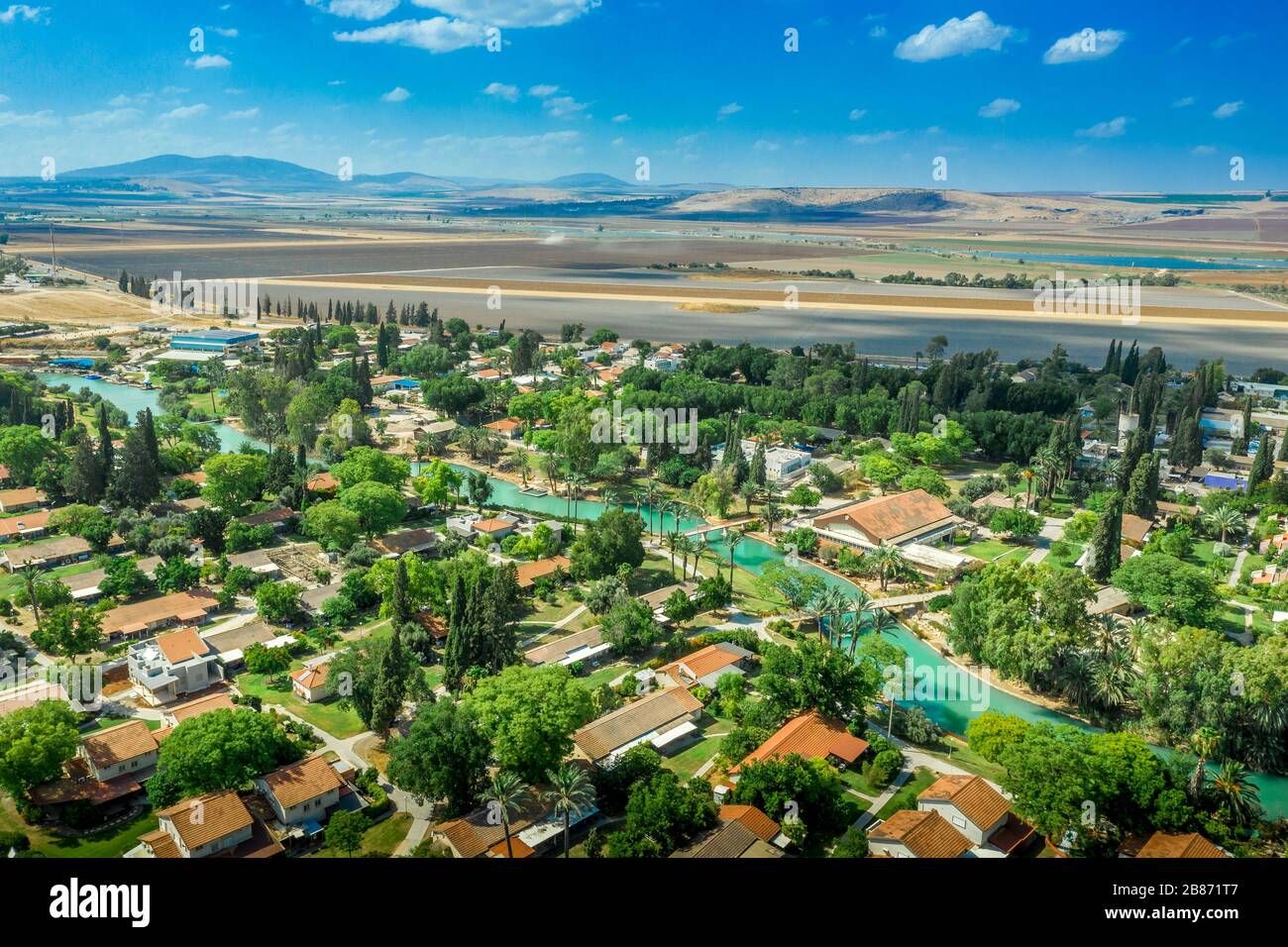 Panorama aereo del fiume turchese Amal che attraversa la comunità collettiva tradizionalmente basata sull'agricoltura Kibbutz NIR David in Israele Foto Stock