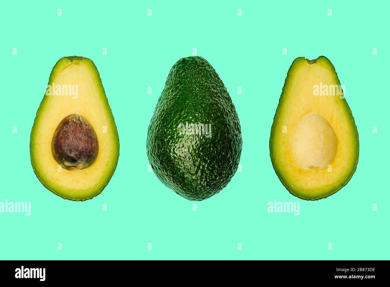 Avocado intero e affettato su sfondo colorato. Mangiare sano e concetto estivo. Foto Stock