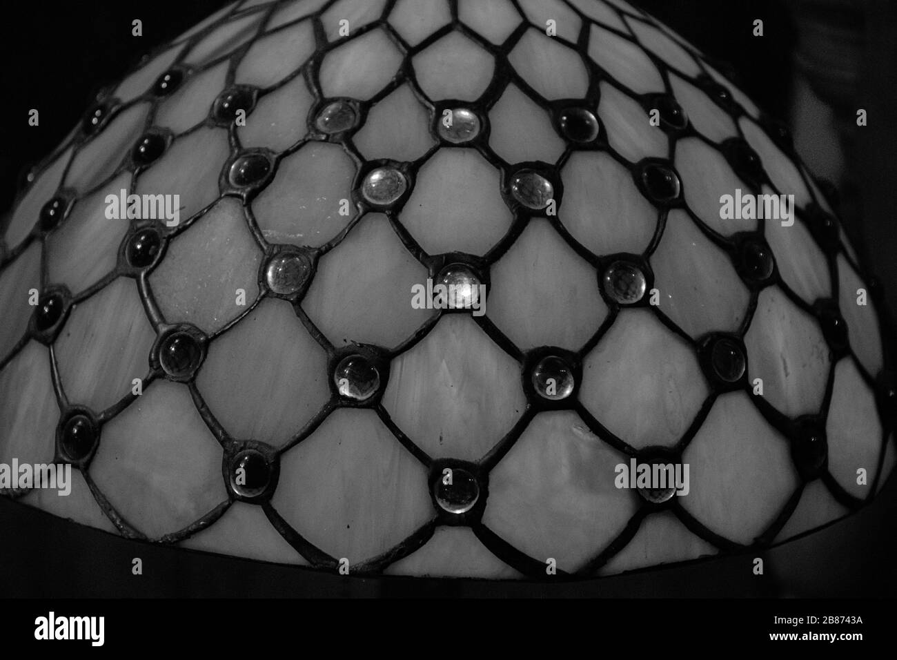 Foto in bianco e nero su una superficie di vetro colorato con motivo rombico e punti di gemme di vetro frizzante. Struttura opaca di antico paralume di vetro d'epoca Foto Stock