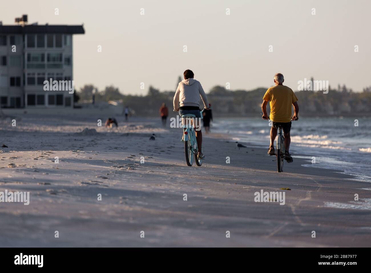 Lido Beach, Florida, Stati Uniti - 20 marzo 2020. Una coppia guida le biciclette lungo Lido Beach subito dopo l'alba. Foto Stock