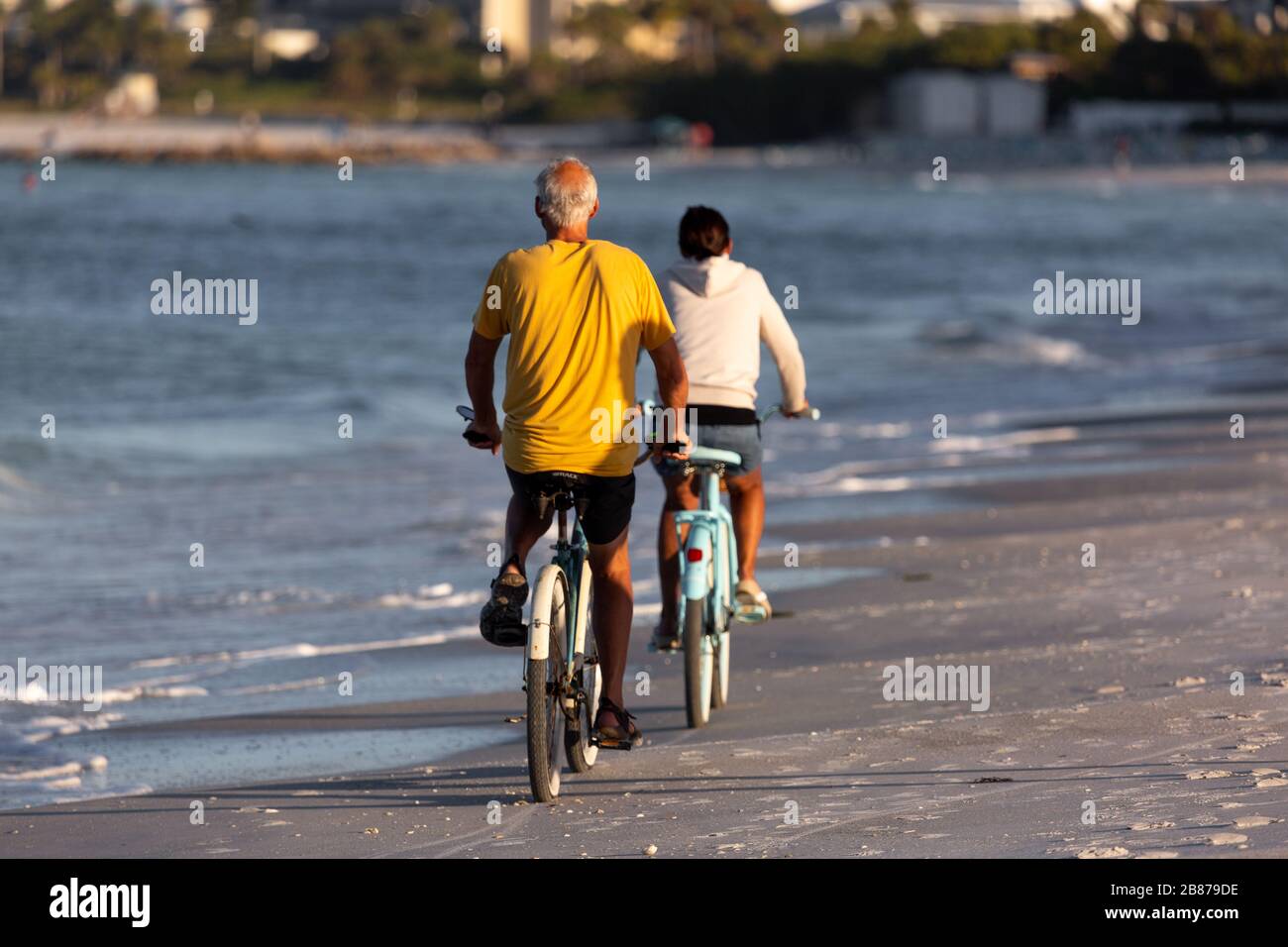 Lido Beach, Florida, Stati Uniti - 20 marzo 2020. Una coppia guida le biciclette lungo Lido Beach subito dopo l'alba. Foto Stock
