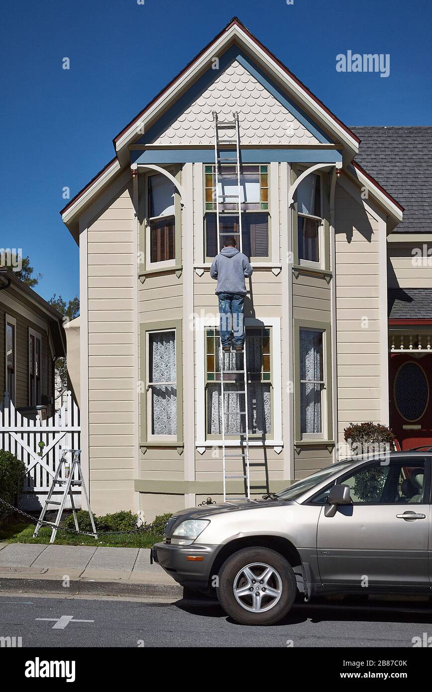 Un artigiano ripara la facciata di una casa vittoriana in legno a Pacific Grove. Foto Stock