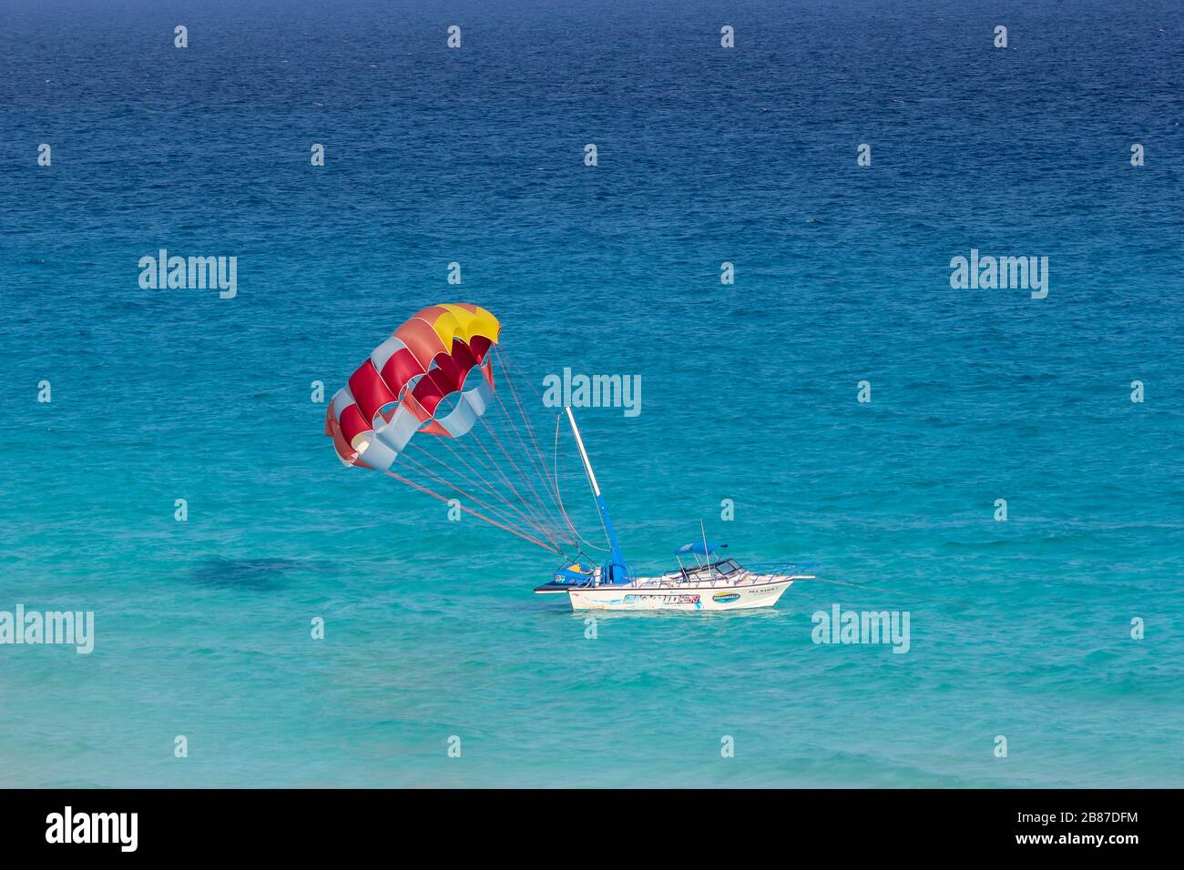 Parasailing barca sulle acque di una spiaggia nella zona Hotel, Cancun, Quintana Roo, Yucatan Peninsula, Messico Foto Stock