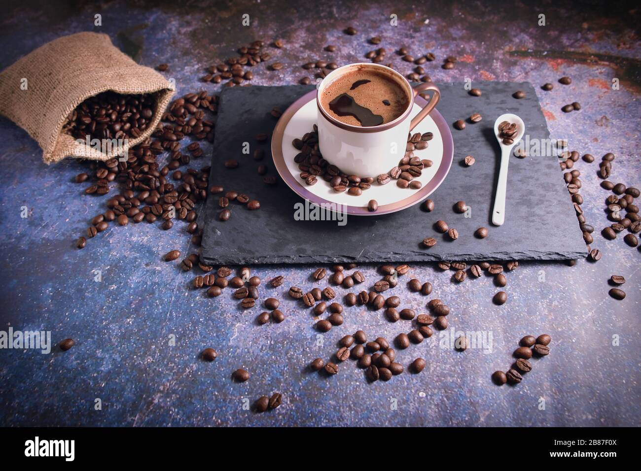 Chicchi di caffè marroni e caffè turco al tavolo rustico. Foto Stock