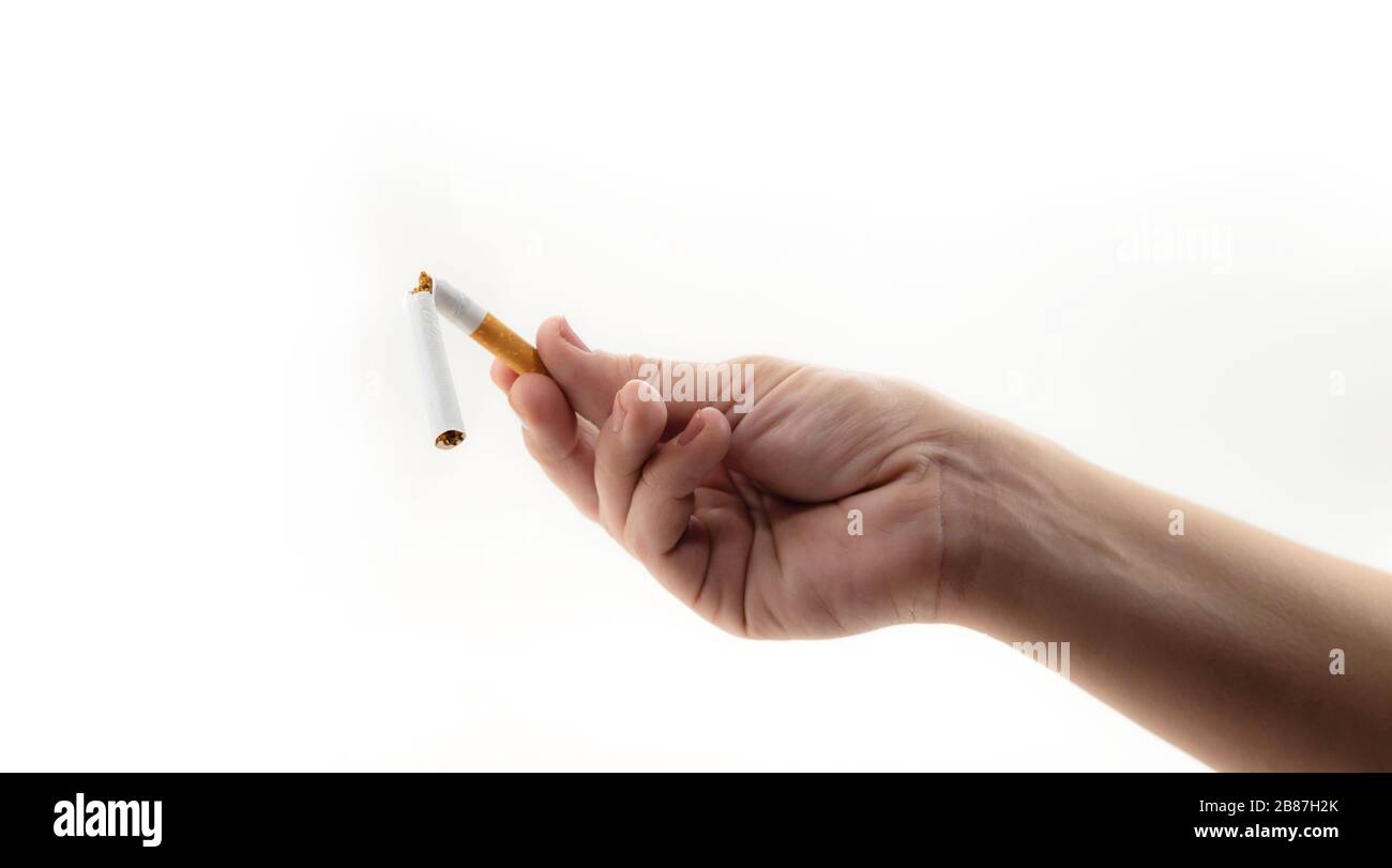 Mano che tiene una sigaretta rotta a causa di smettere di fumare isolato su uno sfondo bianco Foto Stock