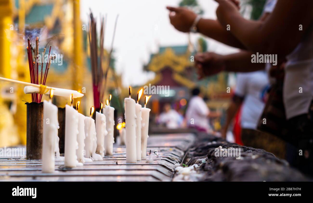 Bruciare candele e incenso in un colorato tempio buddista in Myanmar durante il giorno luce. Foto Stock