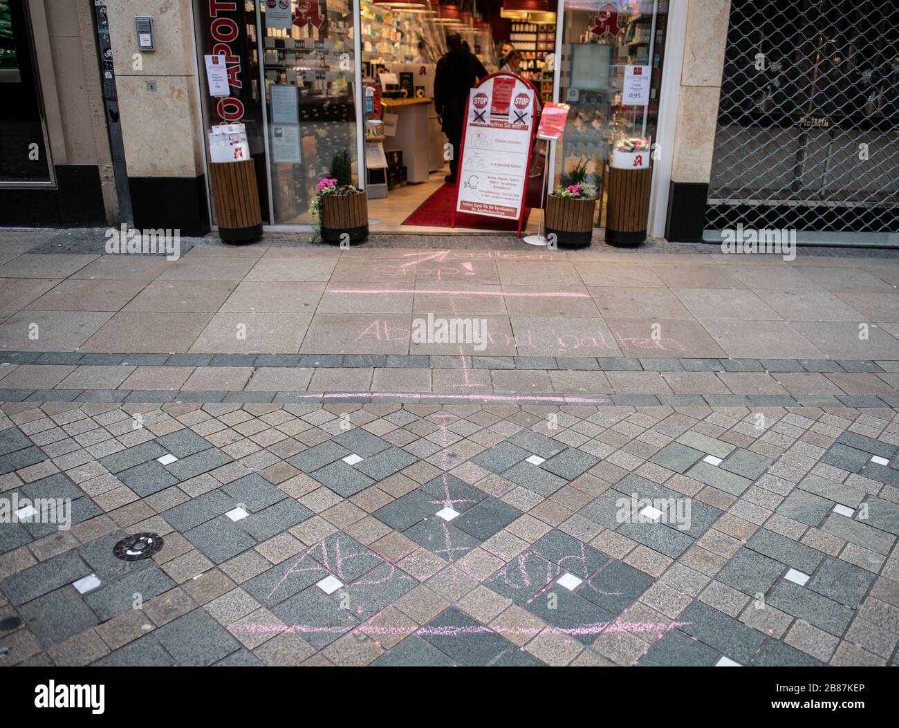 20 marzo 2020, Renania settentrionale-Vestfalia, Dortmund: I contrassegni per tenere lontani i clienti sono dipinti con gesso sul pavimento di fronte ad una farmacia. A Dortmund, a causa della pandemia di coronavirus, sono vietate riunioni di più di quattro persone negli spazi pubblici. Foto: Bernd Thissen/dpa Foto Stock