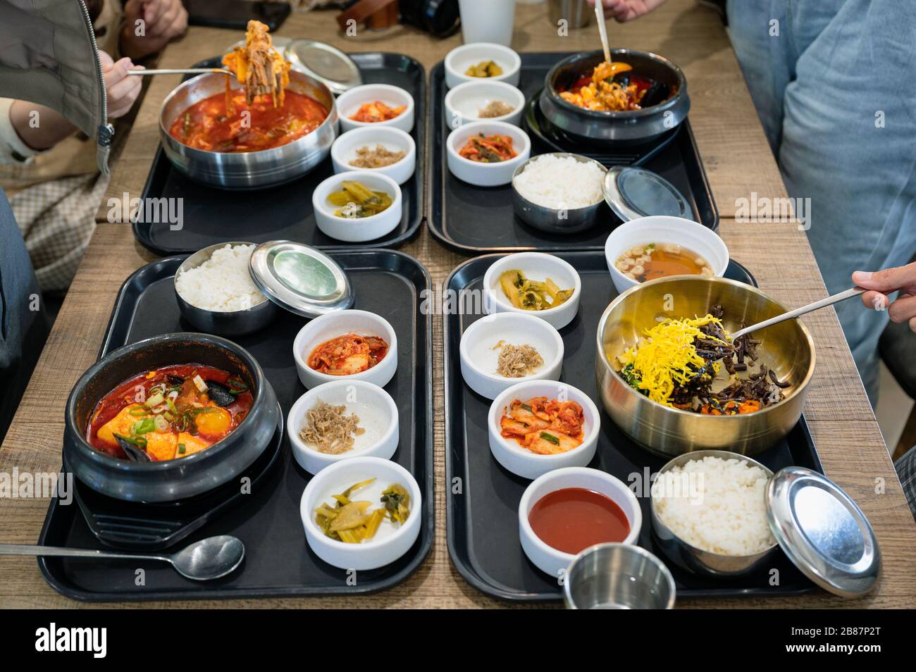 Vari piatti coreani con zuppa piccante, kimchi, tagliatelle e sottaceti di verdure sul vassoio del ristorante Foto Stock