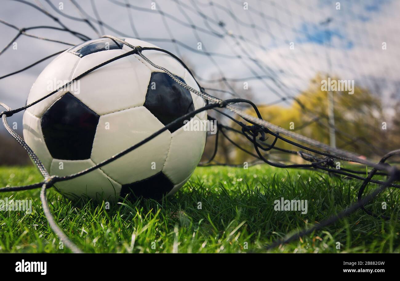 Primo piano di una palla di calcio entra nel cancello e colpisce la rete, concetto di obiettivo. Campionato di calcio, tornei primaverili all'aperto. Sport sano Foto Stock