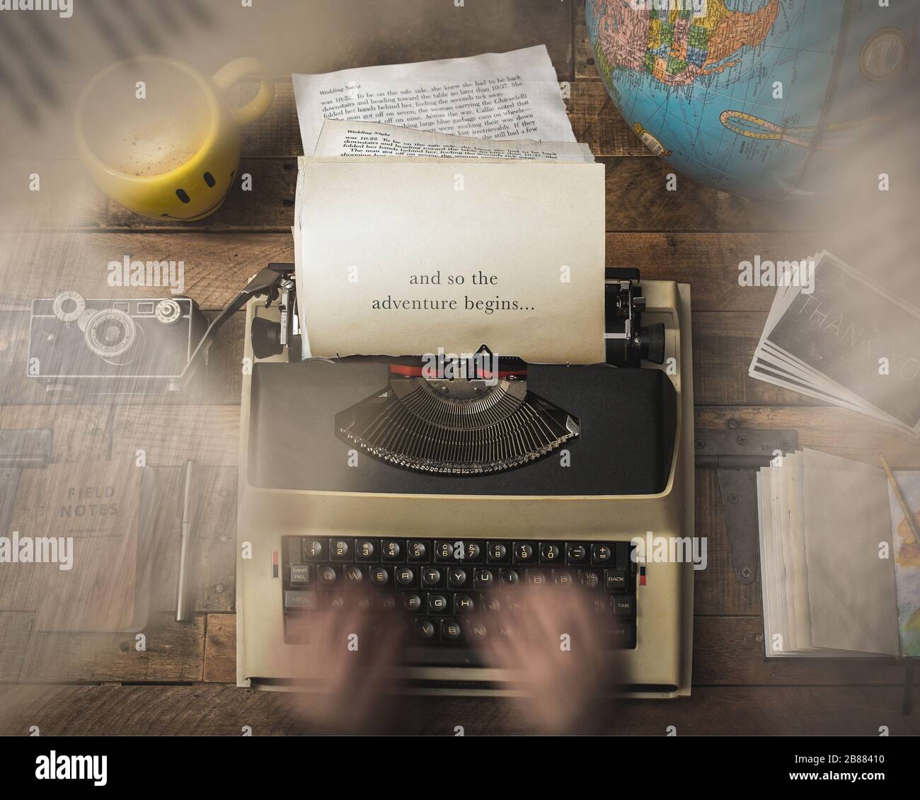 E così l'avventura inizia a scrivere la tua storia su una macchina da scrivere con una tazza di caffè, macchina fotografica vintage e globo su una scrivania in legno rustico Foto Stock