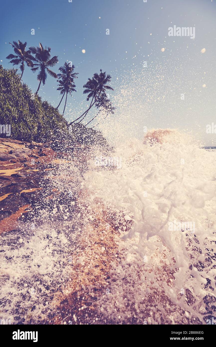 Spiaggia tropicale con onde che si schiantano contro le rocce, colore tonificante applicato, Sri Lanka. Foto Stock