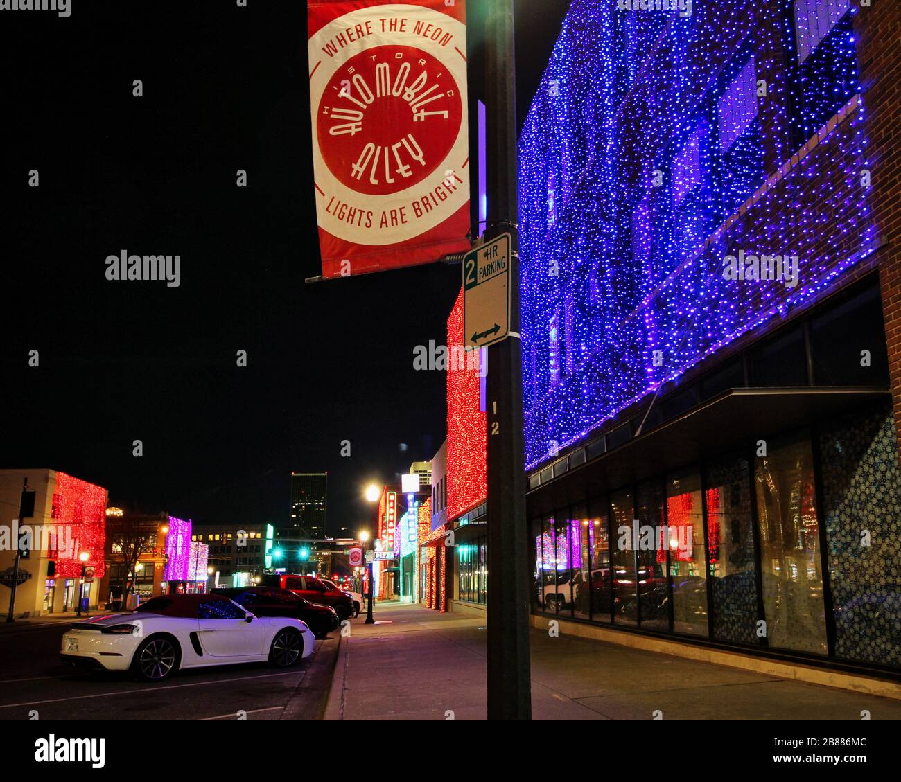 Le auto sono parcheggiate lungo Broadway Avenue, conosciuto anche come Automobile Alley, come le luci festive di festa drappeggiano gli edifici degli affari. Foto Stock