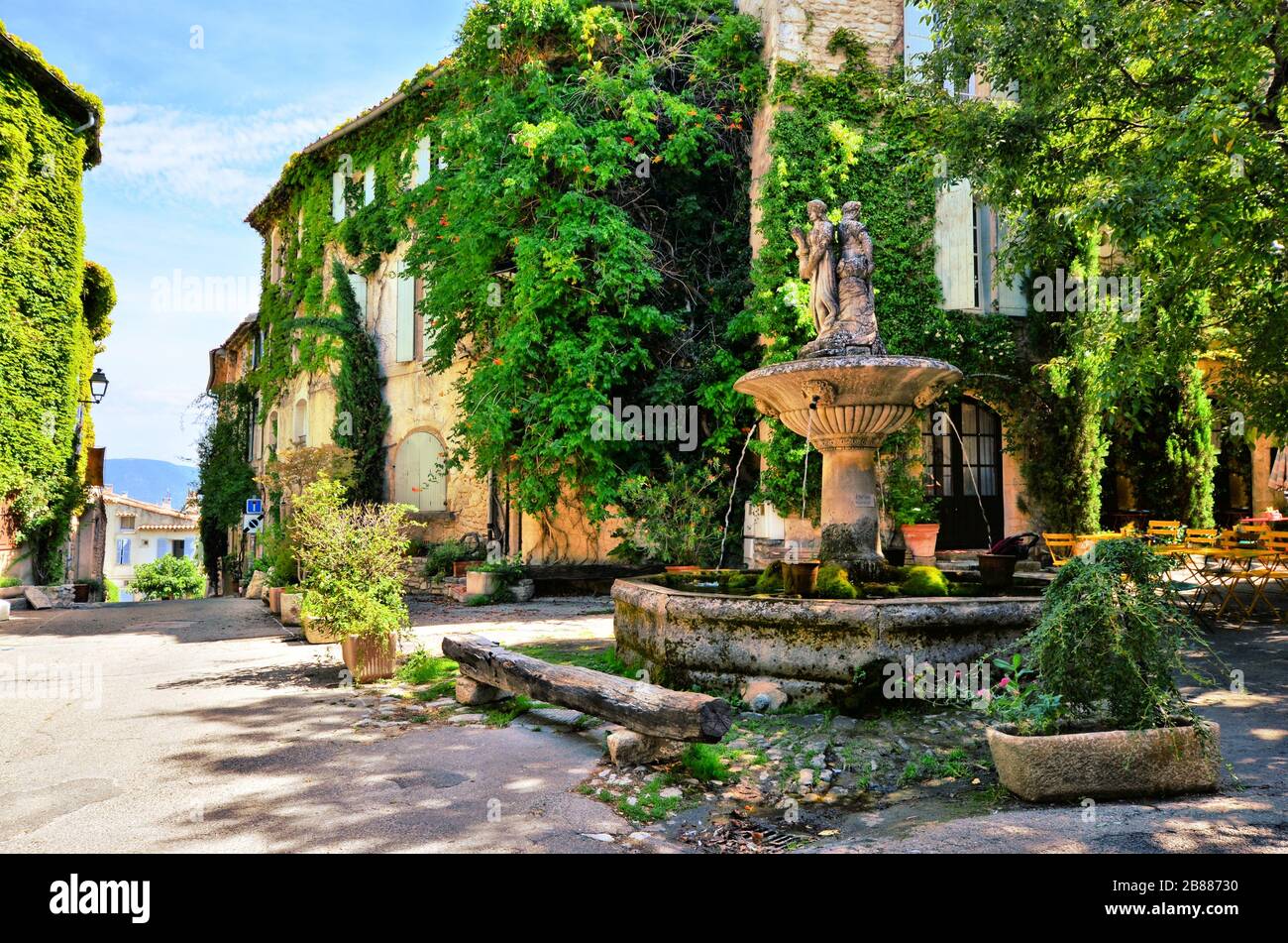 Frondosa piazza della città con fontana in un pittoresco villaggio in Provenza, Francia Foto Stock