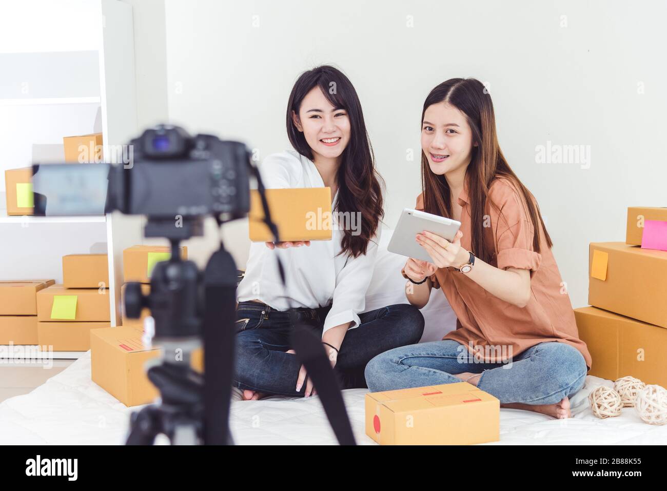 Due donne asiatiche che utilizzano la videocamera digitale per registrare e presentare la pubblicità di nuovi prodotti. Concetto di vlog e influencer. Persone lavoro part-time a Foto Stock