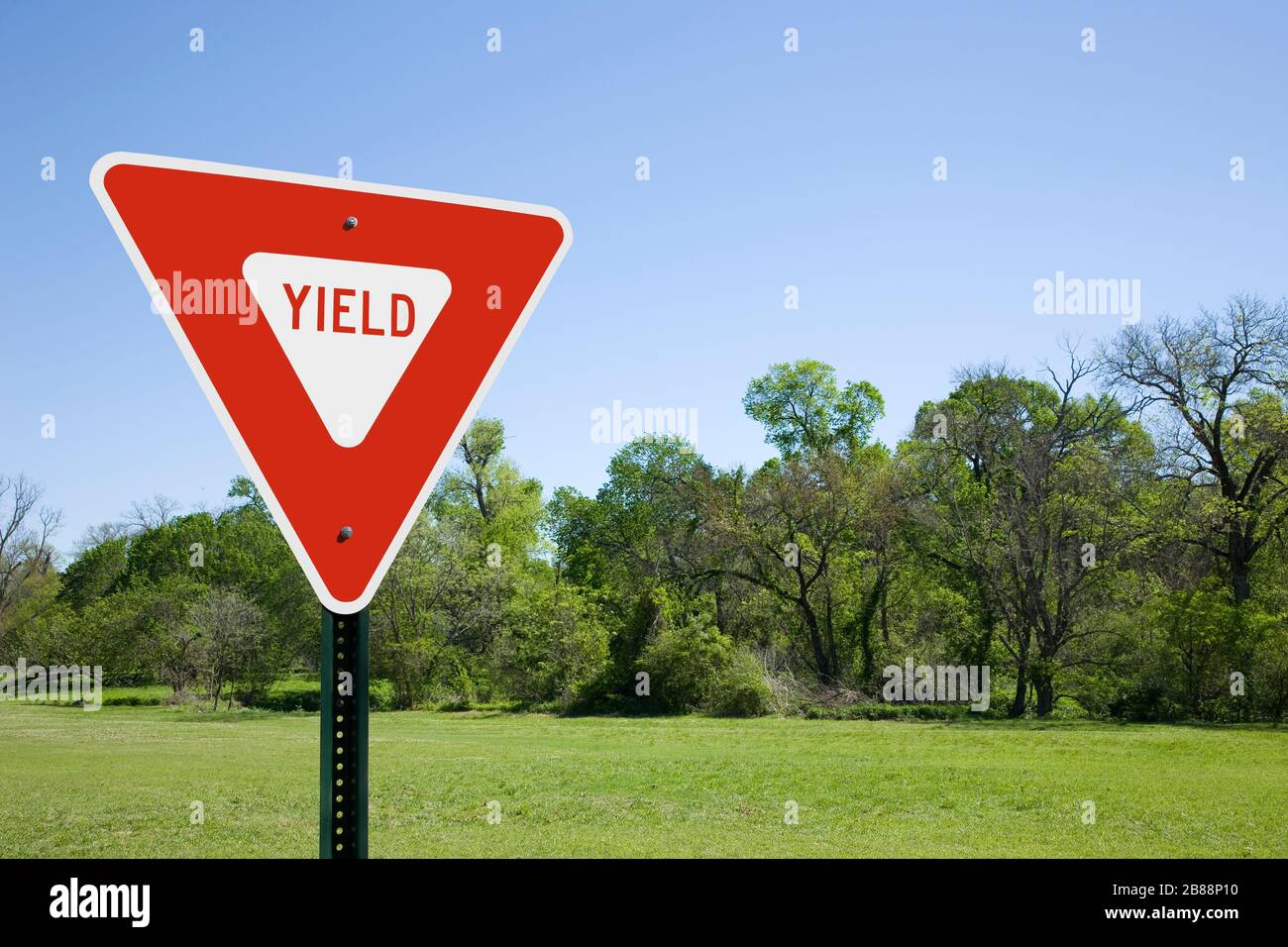Red Yield Sign in a Sunny Landscape Foto Stock
