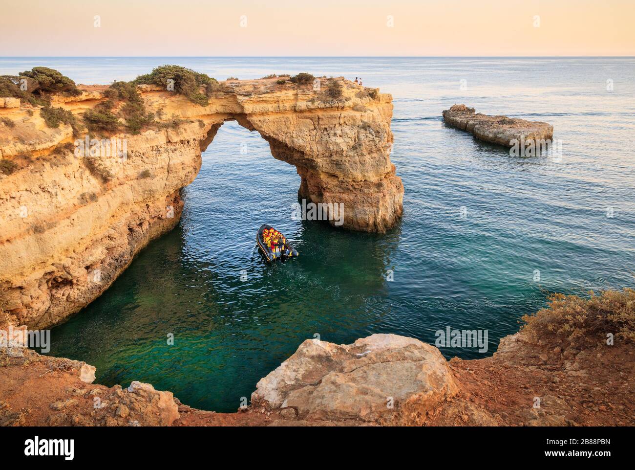 Portici, Portogallo - 24 luglio 2019: Arco di Albandeira. Arco naturale sopra il mare con un tour in barca che passa sotto. Foto Stock