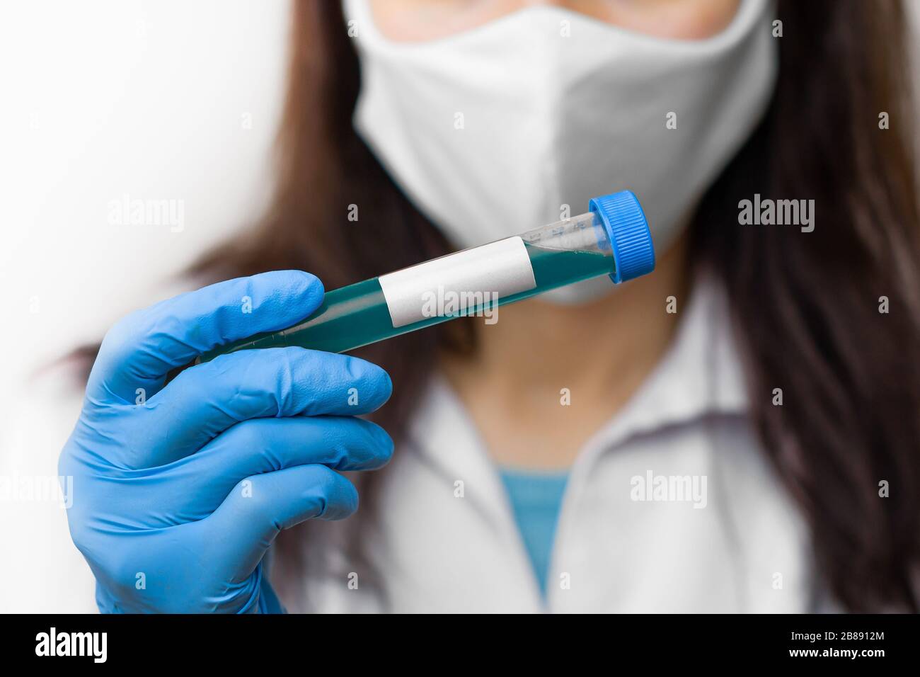 Provetta con vaccino contro il coronavirus, 2019-nCoV, SARS-nCov, COVID-19 in maschera protettiva e guanti blu per scienziato. Foto Stock