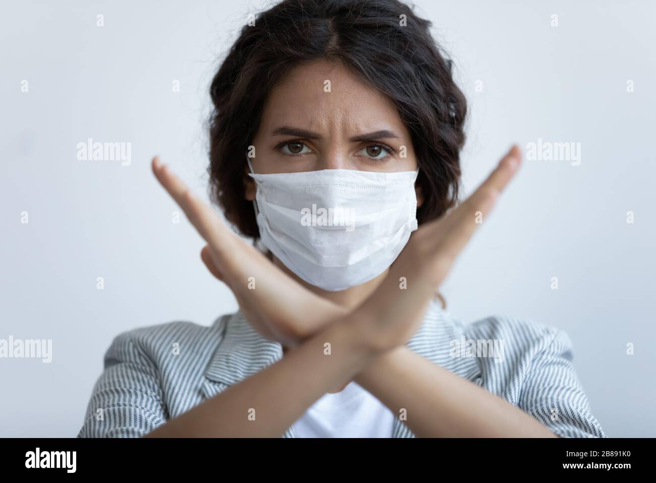 Donna in maschera che mostra il segno No con le braccia incrociate Foto Stock