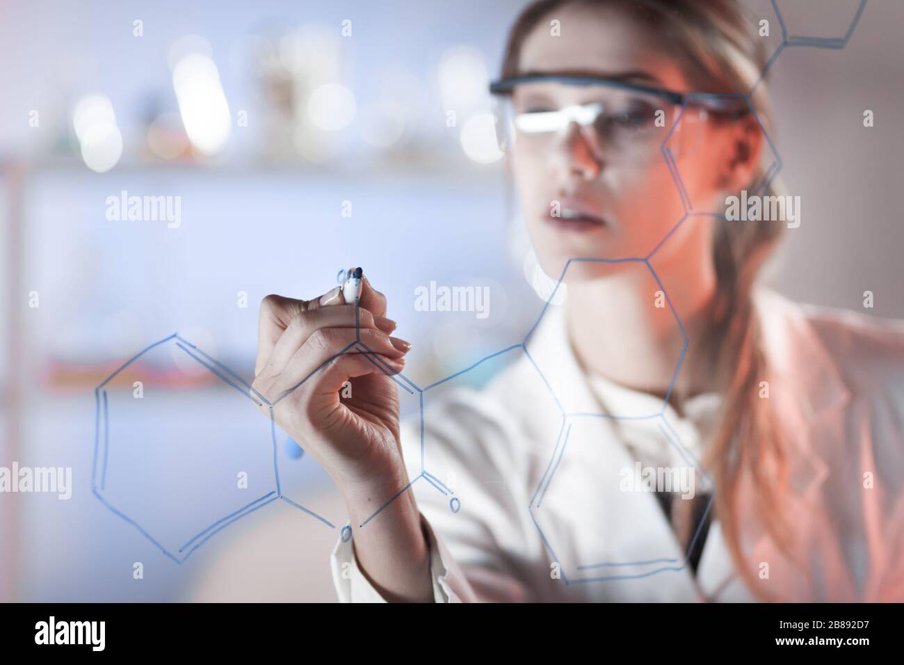 Ritratto di un fiducioso ricercatore femminile nella vita science laboratory iscritto strutturali di formula chimica su un bordo di vetro. Foto Stock