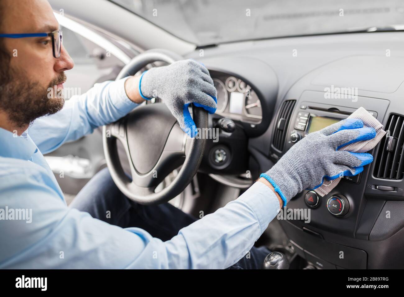 Uomo con guanti di protezione pulizia cruscotto auto con panno in  microfibra Foto stock - Alamy