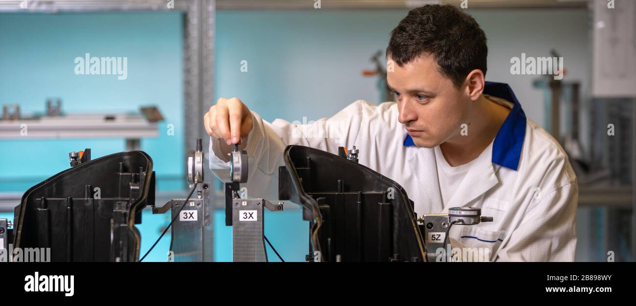 L'ingegnere misura i componenti in plastica per la produzione di luci per l'industria automobilistica in una fabbrica su una macchina digitale 3D Foto Stock